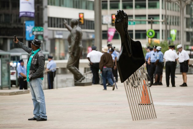 A man takes a selfie in front of Thomas’s sculpture of a 12-foot Afro pick, called All Power to All People, in view of a statue of Philadelphia’s former mayor and police commissioner Rizzo (Matt Rourke/AP/CP)